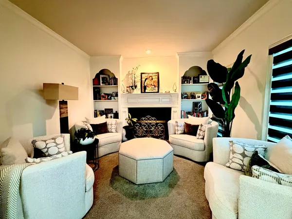 Cream sitting room with a painted fireplace, built-in shelving either side and bay seating